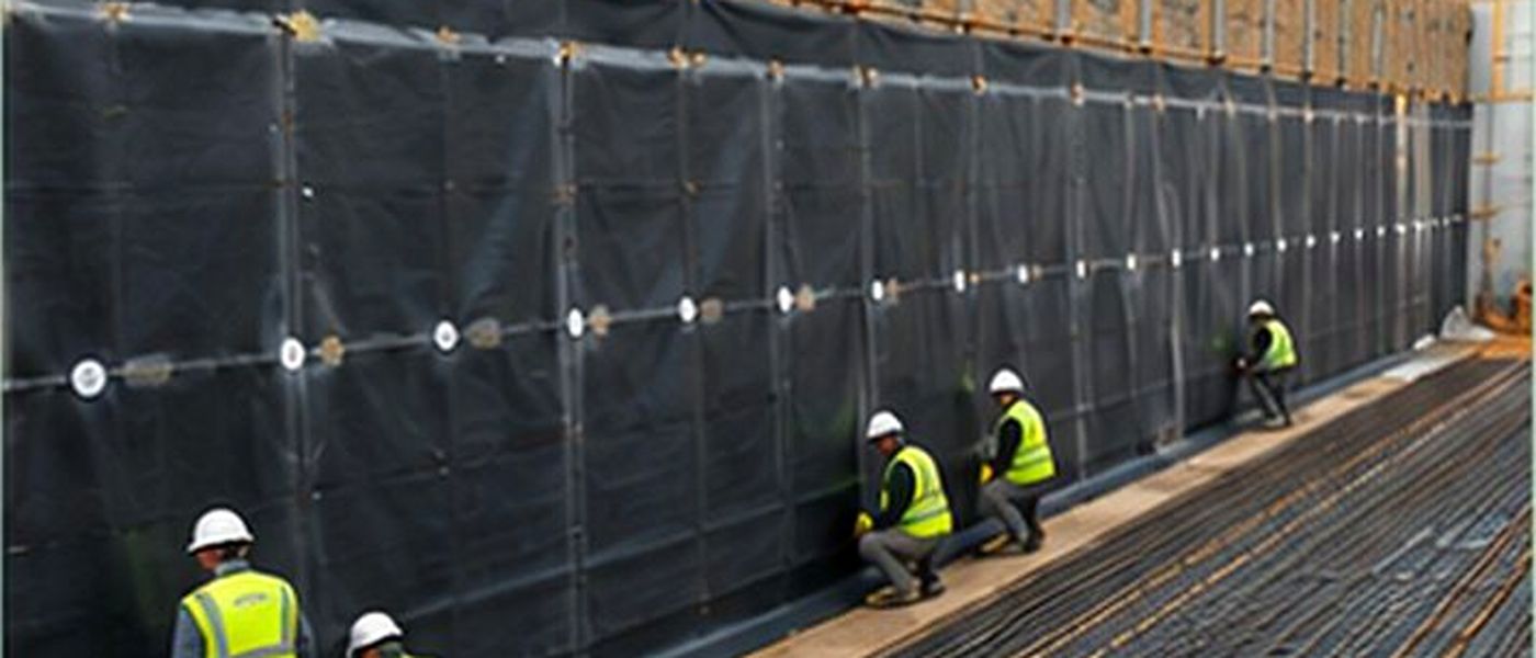 Laying a bentonite geocomposite on a retaining wall